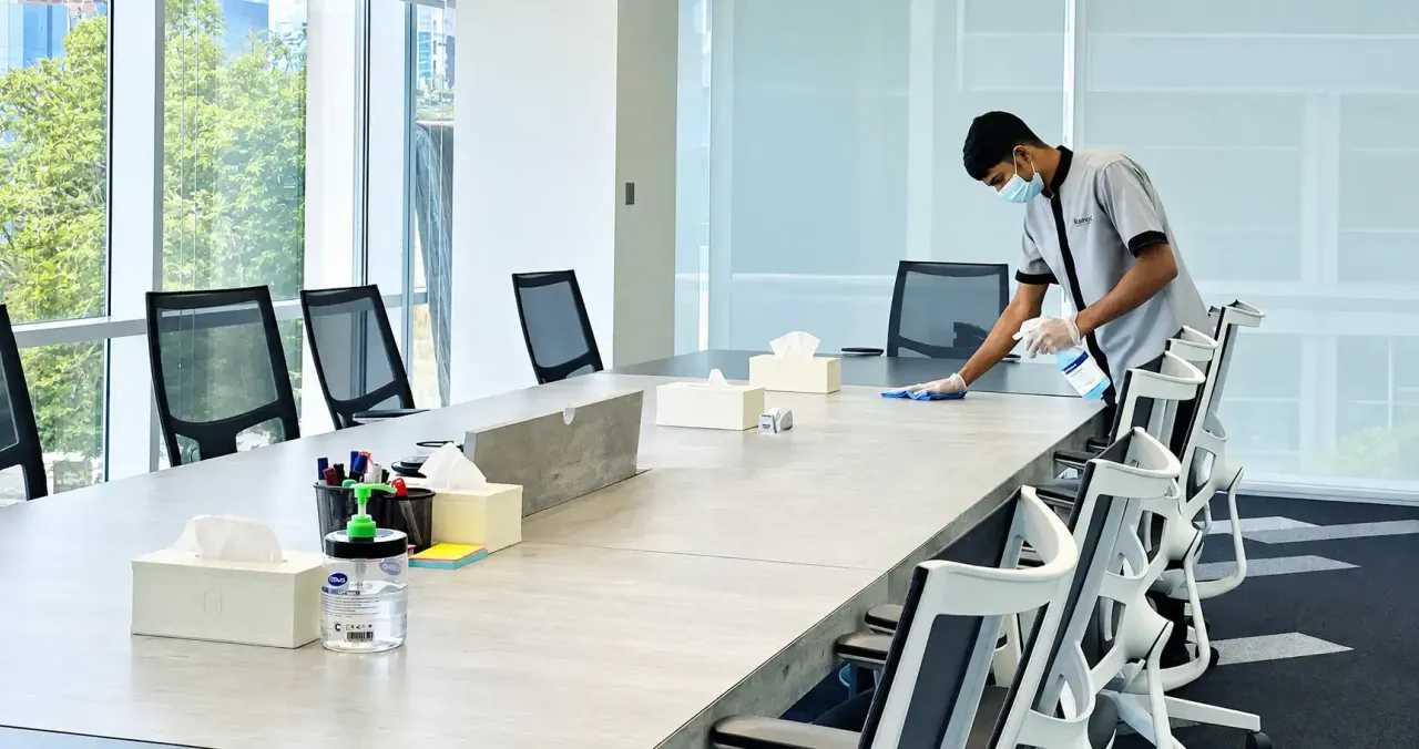 An iScience cleaner wiping down an office meeting table